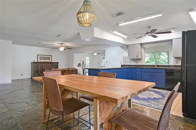 a kitchen with stainless steel appliances kitchen island granite countertop a table chairs and a refrigerator