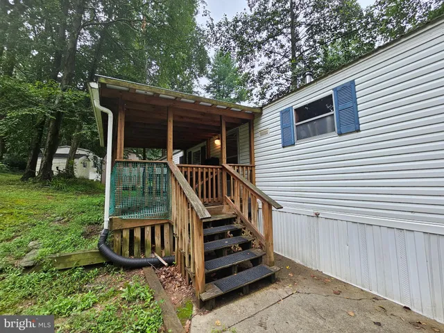 a view of a small house with wooden fence and a large tree