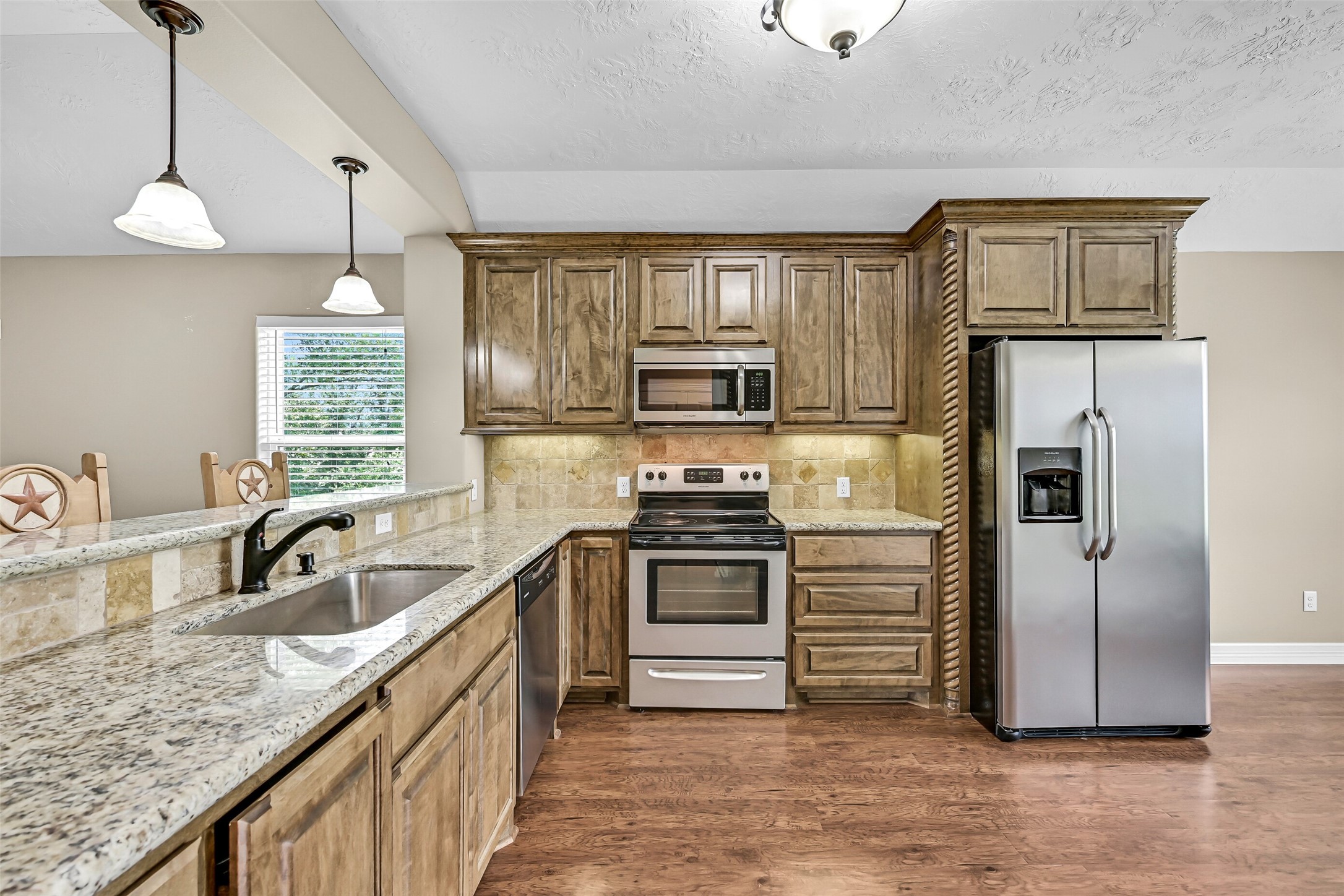 11930 Bastrop Beach Road Angleton, TX 77515 - Photo 4 of 29 Designed to be both beautiful and functional, the kitchen features custom cabinetry, granite countertops, a tumbled stone backsplash, stainless steel appliances, undermount sink, bartop seating, and generous prep space for everything from everyday meals to weekend gatherings.