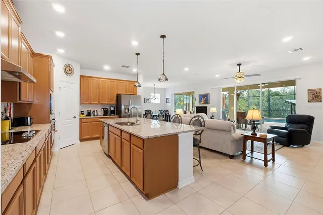 a large kitchen with kitchen island granite countertop a large counter top stainless steel appliances a rug a stove and a view of living room