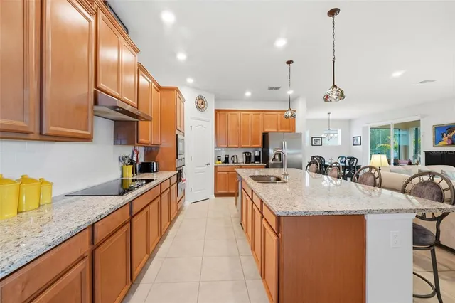 a open kitchen with stainless steel appliances granite countertop a sink a oven a dining table chairs and view living room
