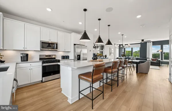 a kitchen with stainless steel appliances kitchen island granite countertop a stove top oven a sink a dining table and chairs with wooden floor