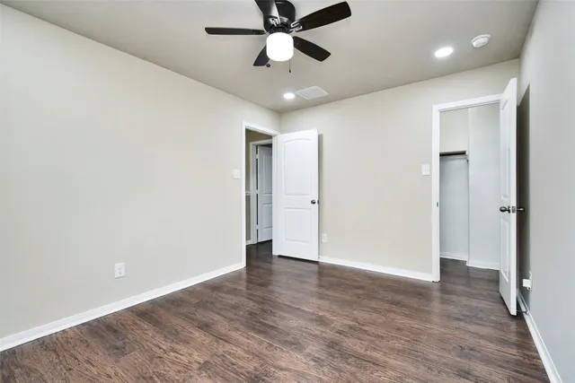 an empty room with wooden floor and ceiling fan