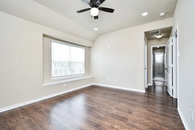 an empty room with wooden floor fan and windows