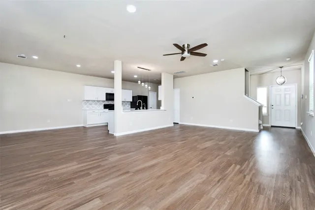 a view of an empty room with wooden floor and a ceiling fan