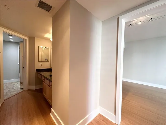 a view of a hallway with wooden floor and a bathroom