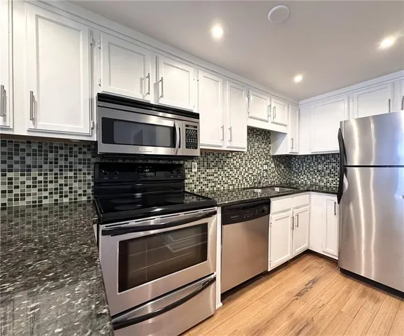 a kitchen with granite countertop a refrigerator stove and microwave