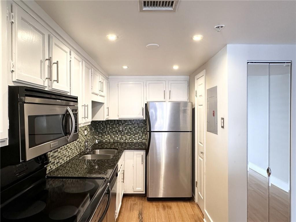 199 14th Street Northeast, Unit 1609 Atlanta, GA 30309 - Photo 7 of 22 a kitchen with a refrigerator a stove top oven and cabinets