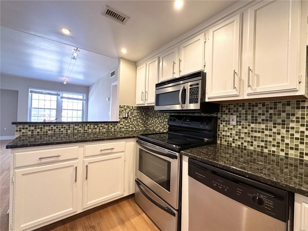 199 14th Street Northeast, Unit 1609 Atlanta, GA 30309 - Photo 10 of 22 a kitchen with granite countertop white cabinets stainless steel appliances and window