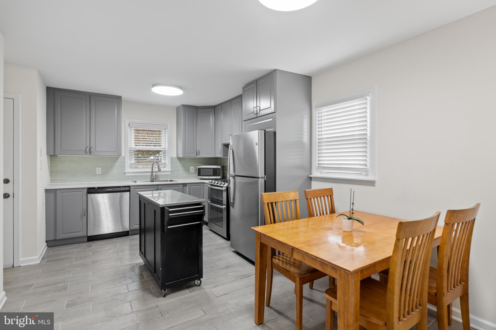 7916 Montrose Avenue Rosedale, MD 21237 - Photo 4 of 28 a kitchen with a refrigerator a stove a sink dishwasher with a dining table and chairs