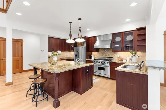 a kitchen with stainless steel appliances granite countertop a sink a stove and a refrigerator