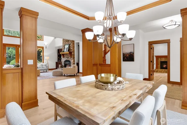 a dining room with wooden floor a chandelier a wooden table and chairs