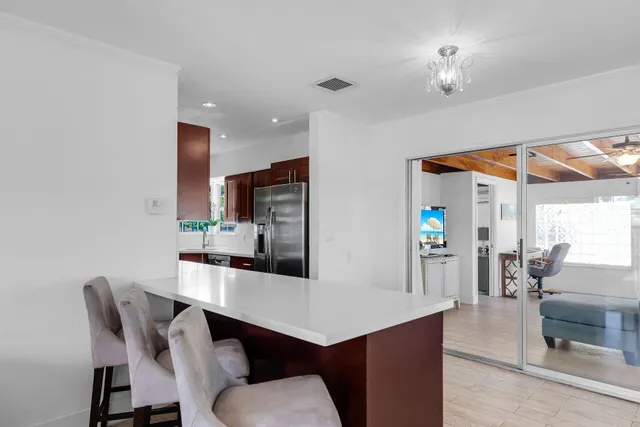 a kitchen with stainless steel appliances kitchen island granite countertop a dining table chairs and a refrigerator