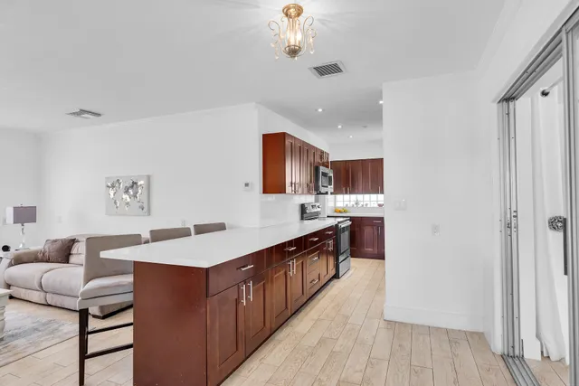 a kitchen with stainless steel appliances granite countertop a refrigerator a sink dishwasher a stove and a dining table with wooden floor