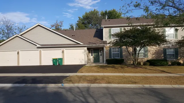 a view of a white house with a large windows and a yard with plants and large trees