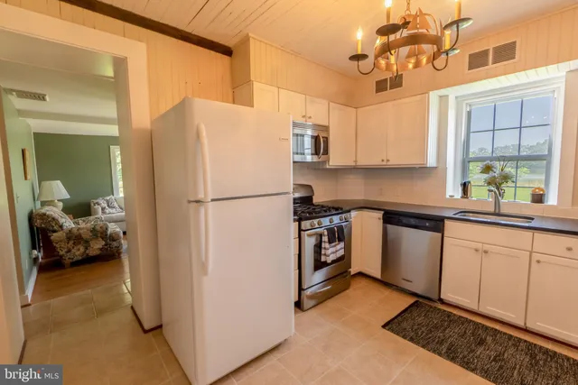 a kitchen with kitchen island a counter top space a sink a refrigerator cabinets and a window
