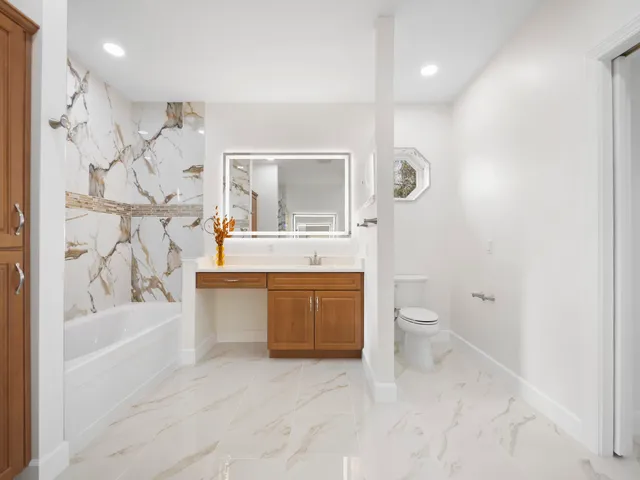 a bathroom with a granite countertop sink mirror and a bathtub