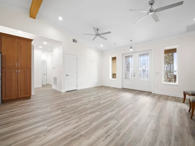 an empty room with wooden floor ceiling fan and windows