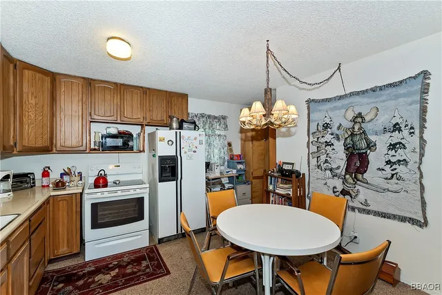 a kitchen with stainless steel appliances granite countertop a refrigerator a sink dishwasher a dining table and chairs with wooden floor