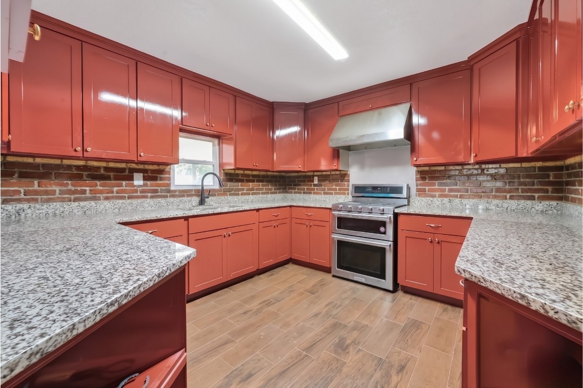 6014 Linda Drive Rosharon, TX 77583 - Photo 10 of 23 This functional U-shaped kitchen features expansive granite countertops and a distinctive brick backsplash that complements the warm wood-look flooring.