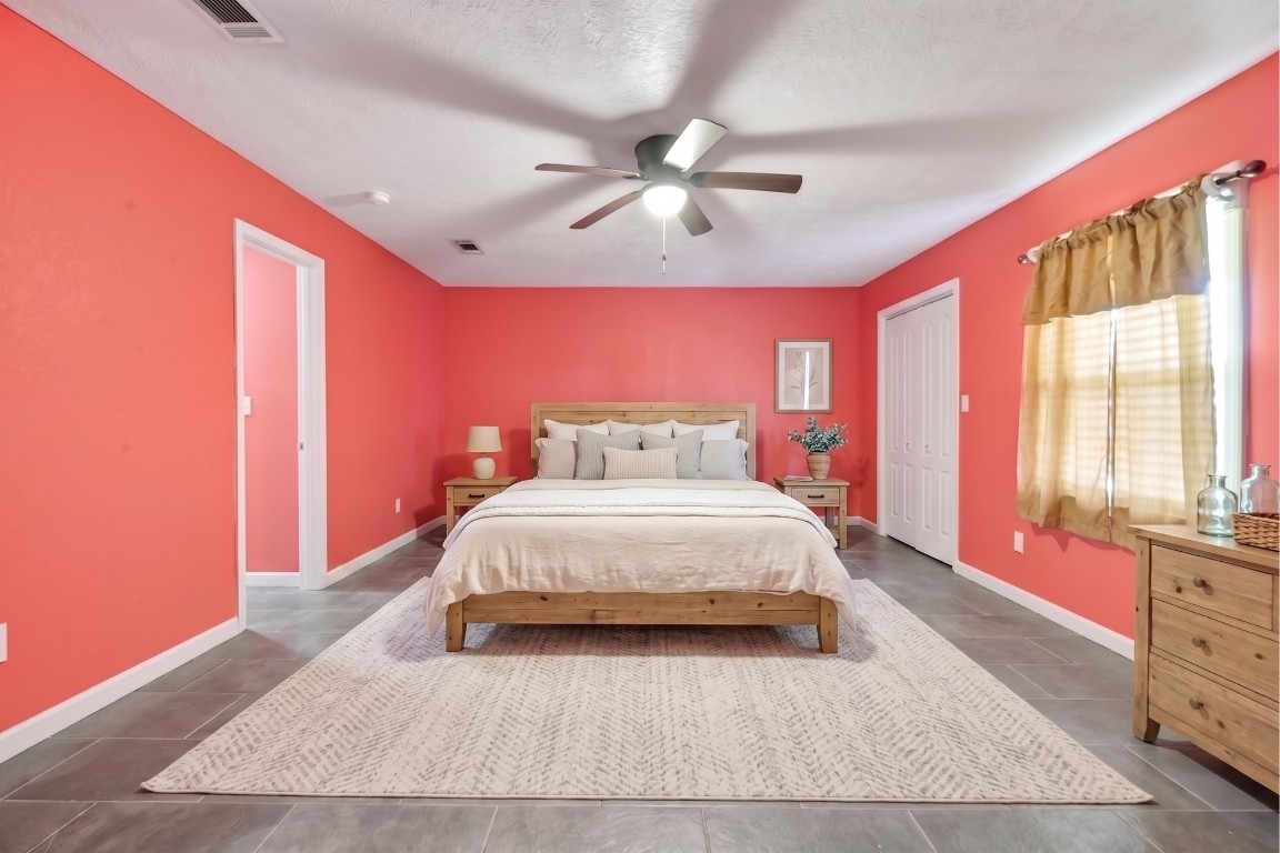 6014 Linda Drive Rosharon, TX 77583 - Photo 18 of 23 Primary bedroom with spacious layout, grey tile flooring, and a ceiling fan, highlighted by bold accent walls.**Virtually staged
