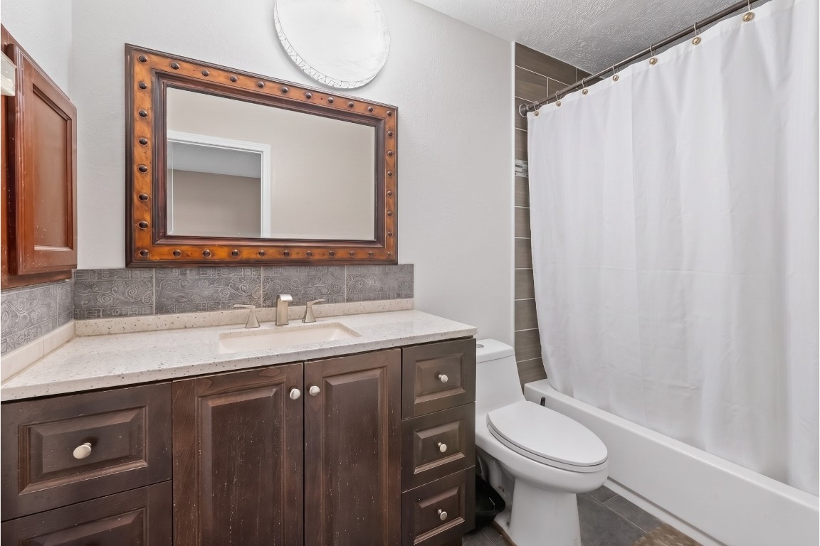 6014 Linda Drive Rosharon, TX 77583 - Photo 20 of 23 This full bathroom features a wide dark-wood vanity with an integrated white basin, along with a convenient tub and shower combo framed by modern oversized wall tiles.