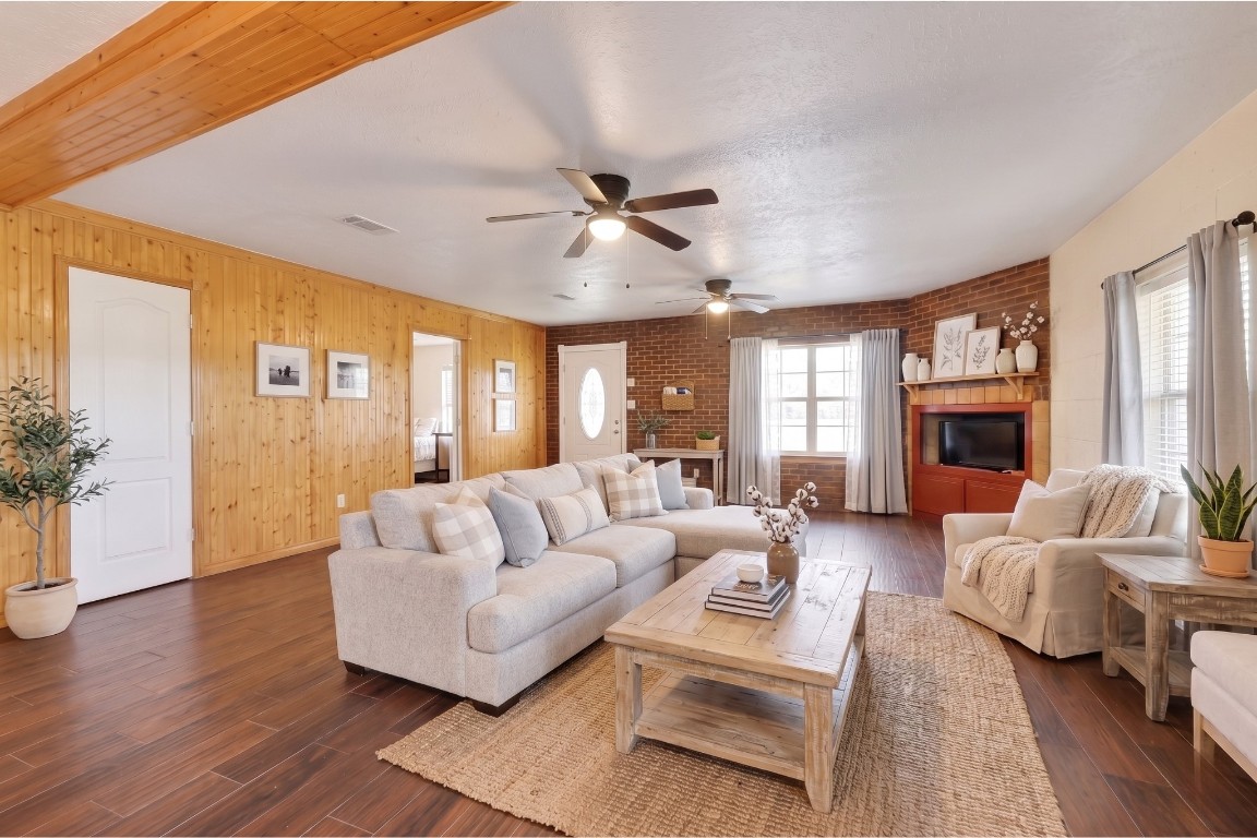 6014 Linda Drive Rosharon, TX 77583 - Photo 4 of 23 Classic wood-paneled walls and exposed brick accents frame the expansive open-concept living area featuring durable wood-look tile flooring and dual ceiling fans.**Virtually staged