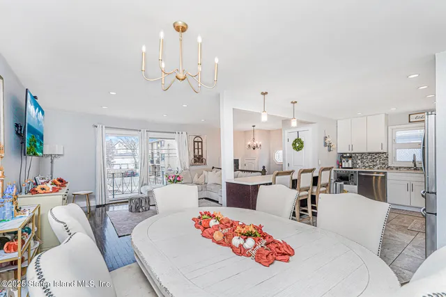a living room with furniture a chandelier and kitchen view