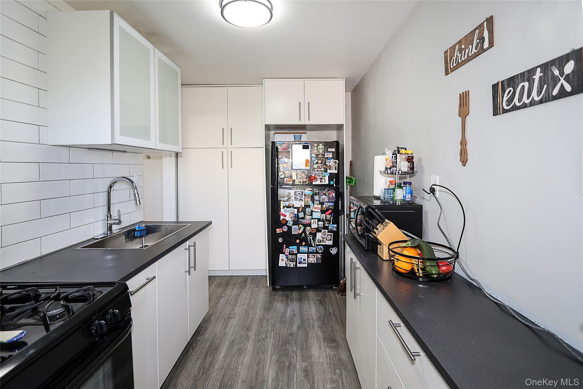 147-10 84th Road, Unit 6K Queens, NY 11435 - Photo 14 of 21 Kitchen featuring dark countertops, dark wood finished floors, and white cabinets