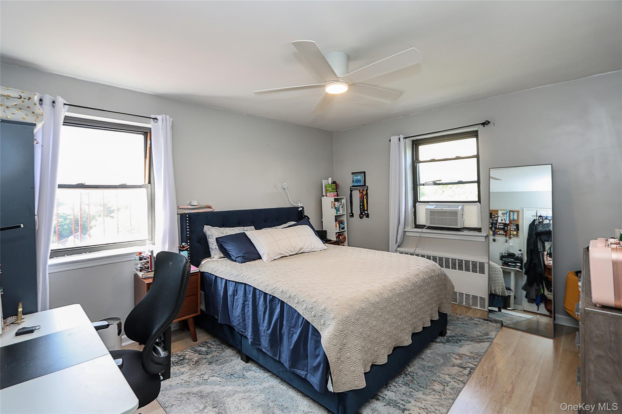 147-10 84th Road, Unit 6K Queens, NY 11435 - Photo 16 of 21 Bedroom with light wood-style floors, radiator heating unit, ceiling fan, and an office area