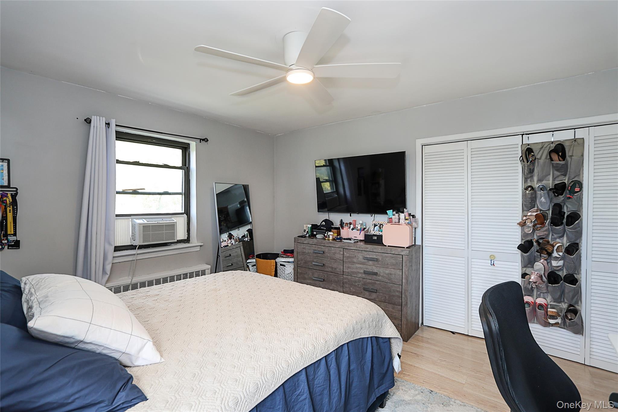 147-10 84th Road, Unit 6K Queens, NY 11435 - Photo 17 of 21 Bedroom with light wood finished floors, ceiling fan, radiator, a closet, and cooling unit