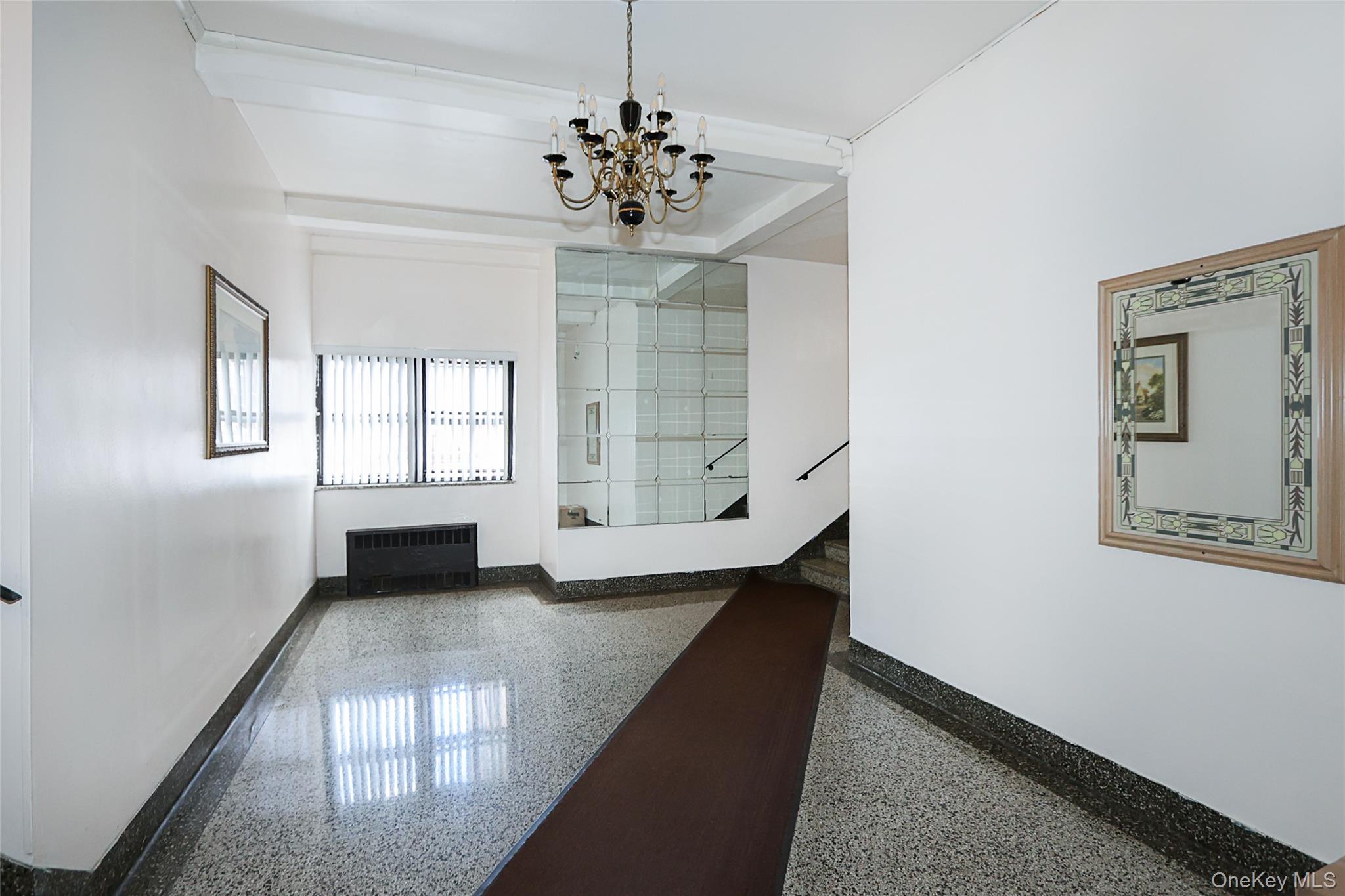 147-10 84th Road, Unit 6K Queens, NY 11435 - Photo 21 of 21 Hallway featuring radiator, stairway, a chandelier, and beam ceiling