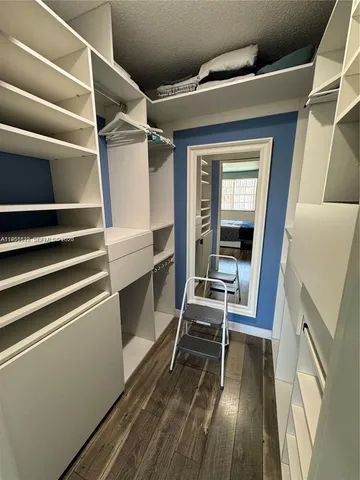 a view of walk in closet with wooden floor and furniture