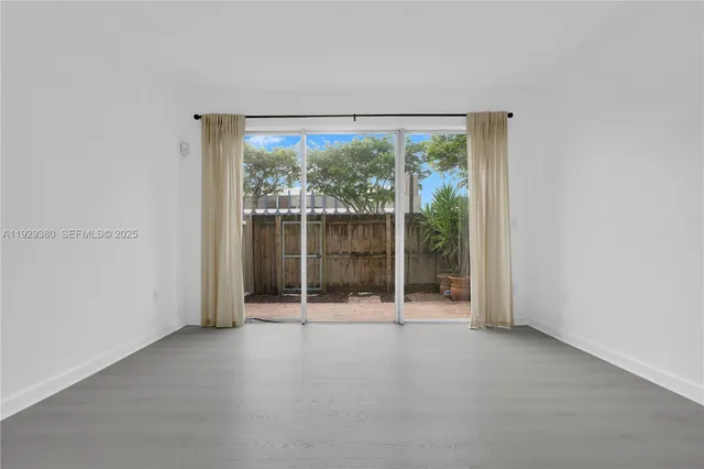 an empty room with sliding glass door and garden