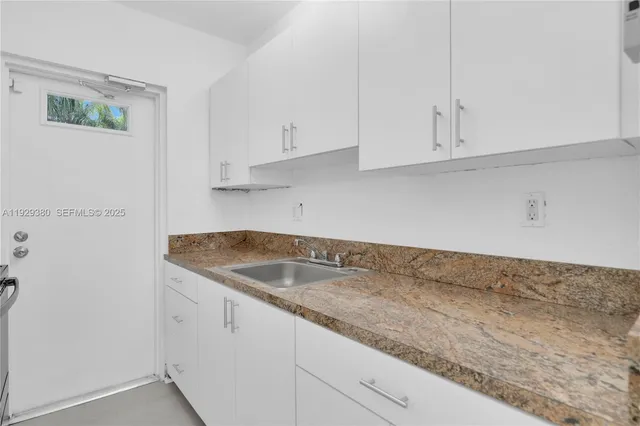 a kitchen with granite countertop white cabinets and a sink
