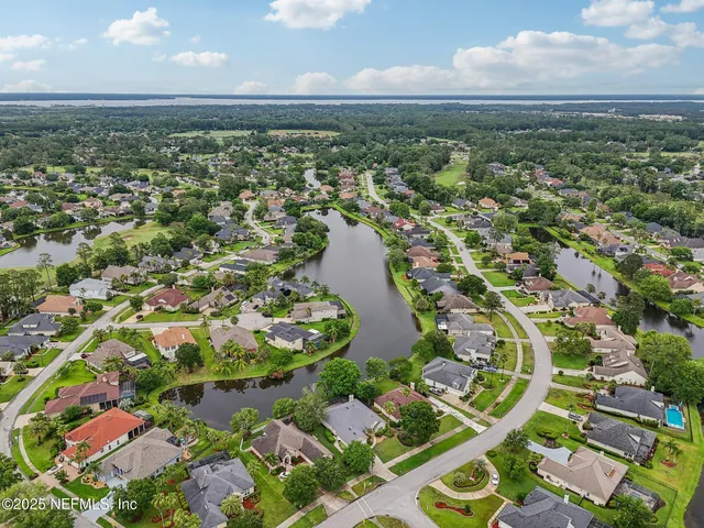 an aerial view of residential houses with outdoor space and trees
