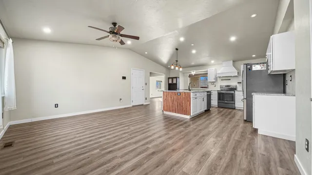 a large white kitchen with wooden floors and stainless steel appliances