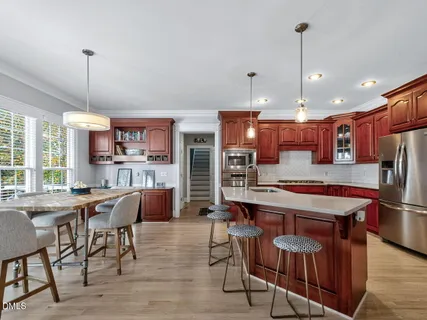 a kitchen with stainless steel appliances kitchen island granite countertop a table chairs and a refrigerator