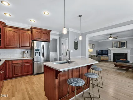 a kitchen with stainless steel appliances granite countertop a sink a stove a refrigerator a dining table and chairs
