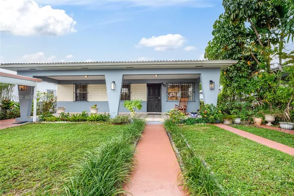 a front view of a house with a yard and potted plants
