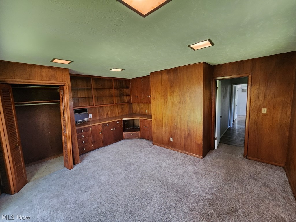 4061 Dartford Road Cleveland, OH 44121 - Photo 13 of 24 Unfurnished bedroom featuring a closet, wood walls, built in desk, and carpet flooring