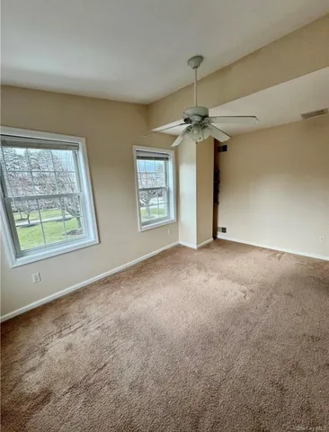 an empty room with windows and chandelier fan