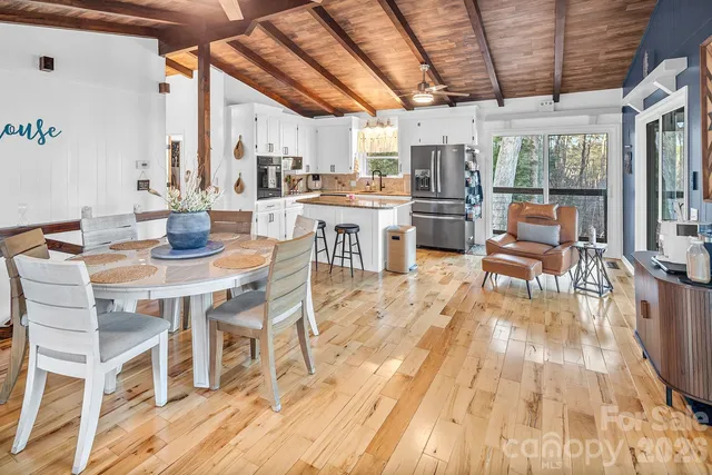 a dining room with furniture a kitchen wooden floor and a chandelier