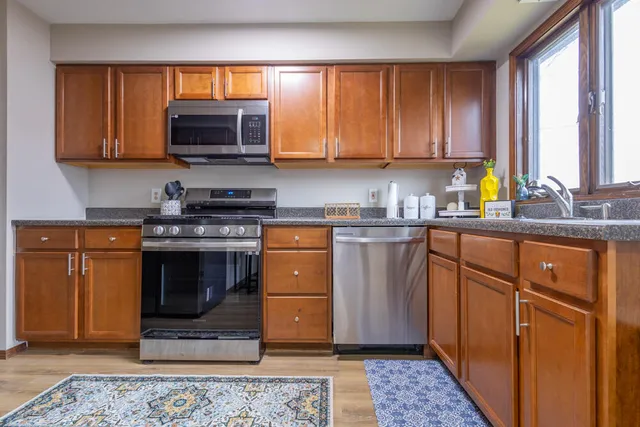 a kitchen with stainless steel appliances granite countertop a stove a sink and a microwave