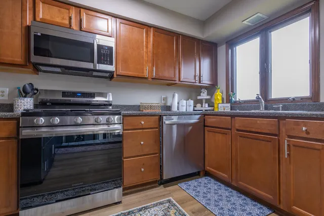 a kitchen with granite countertop wooden cabinets and stainless steel appliances