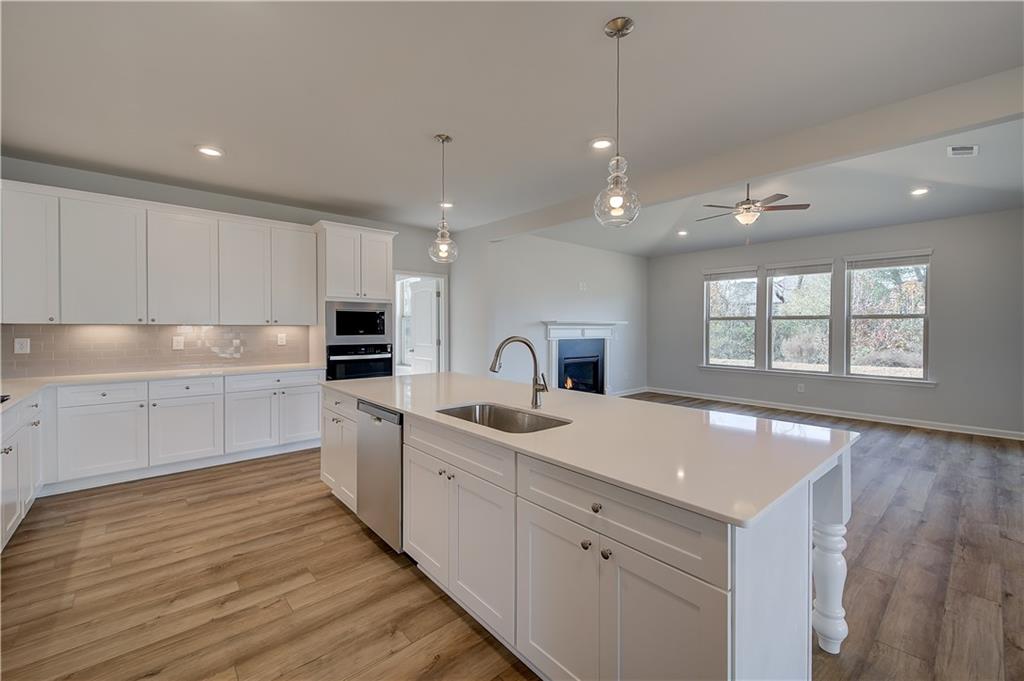 154 Haverling Pass Hampton, GA 30228 - Photo 16 of 36 a kitchen with white cabinets a sink dishwasher and a stove with wooden floor