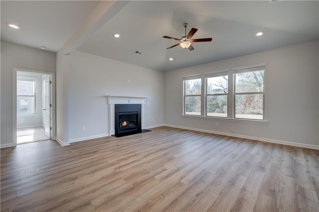 154 Haverling Pass Hampton, GA 30228 - Photo 17 of 36 an empty room with wooden floor fireplace and windows