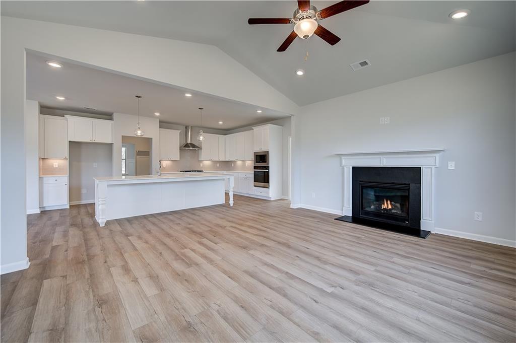 154 Haverling Pass Hampton, GA 30228 - Photo 19 of 36 a view of an empty room and a kitchen with fireplace wooden floor