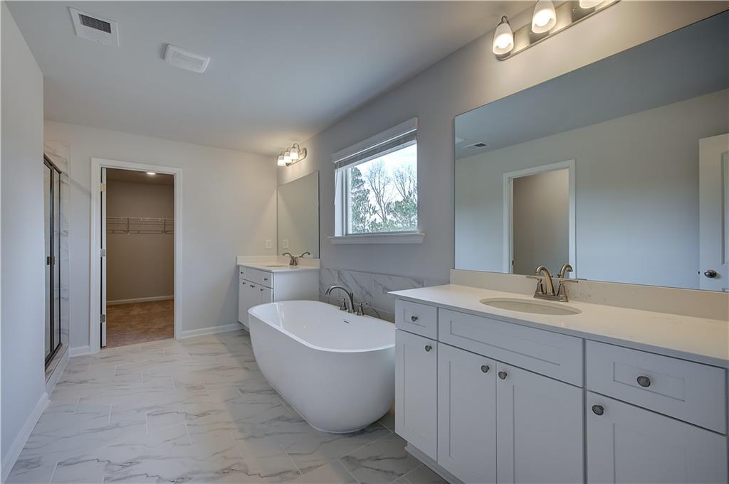 154 Haverling Pass Hampton, GA 30228 - Photo 29 of 36 a spacious bathroom with a double vanity sink a mirror and a bathtub