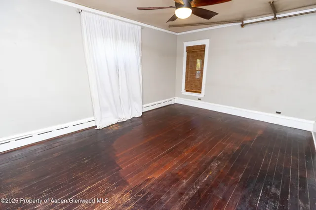 an empty room with wooden floor and a ceiling fan